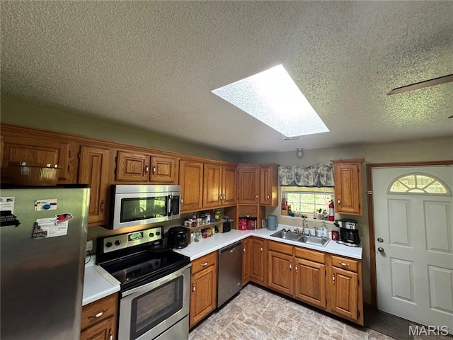 9747 Wayne Route P, Mcgee, MO 63763 - kitchen featuring stainless steel appliances, a skylight, a sink, brown cabinetry, and a textured ceiling