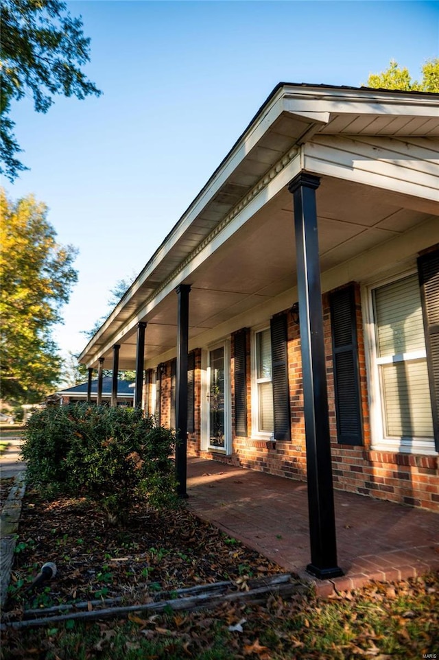 view of property exterior featuring brick siding and a porch