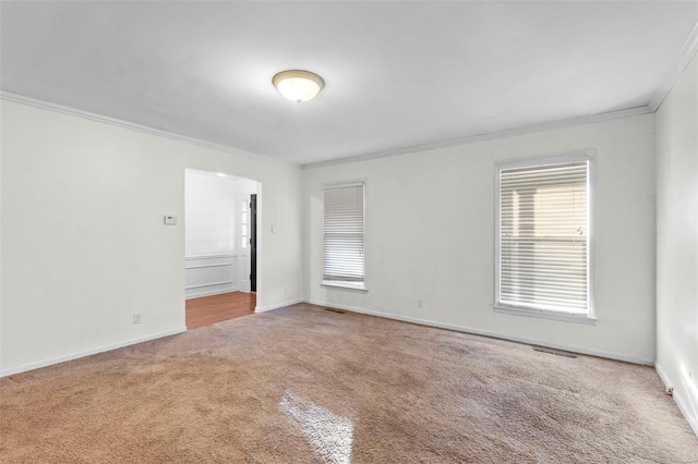 carpeted empty room with ornamental molding and baseboards
