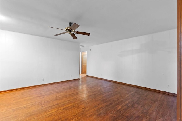 empty room with a ceiling fan, wood finished floors, and baseboards