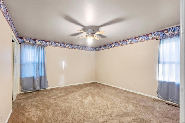 carpeted empty room with a ceiling fan and baseboards