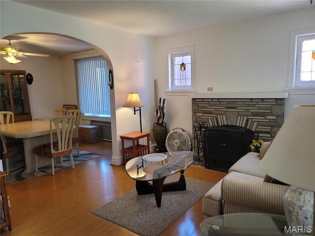 4877 Calvin Ave, Saint Louis, MO 63115 - living area with wood finished floors, a stone fireplace, arched walkways, and ceiling fan
