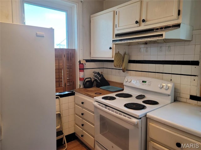 4877 Calvin Ave, Saint Louis, MO 63115 - kitchen with electric stove, freestanding refrigerator, under cabinet range hood, tasteful backsplash, and light countertops