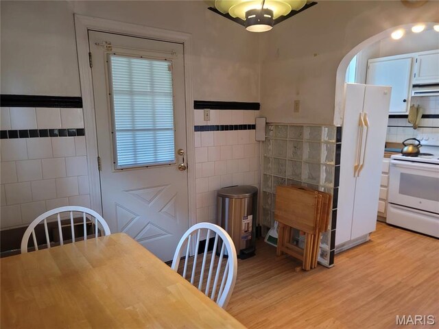 4877 Calvin Ave, Saint Louis, MO 63115 - dining room featuring tile walls, light wood finished floors, and arched walkways