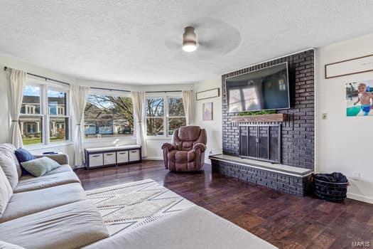 825 Cimarron Cir, Farmington, MO 63640 - living area with a textured ceiling, wood finished floors, a fireplace, a ceiling fan, and baseboards