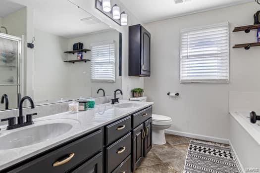 825 Cimarron Cir, Farmington, MO 63640 - full bath with baseboards, an enclosed shower, double vanity, toilet, and a tub