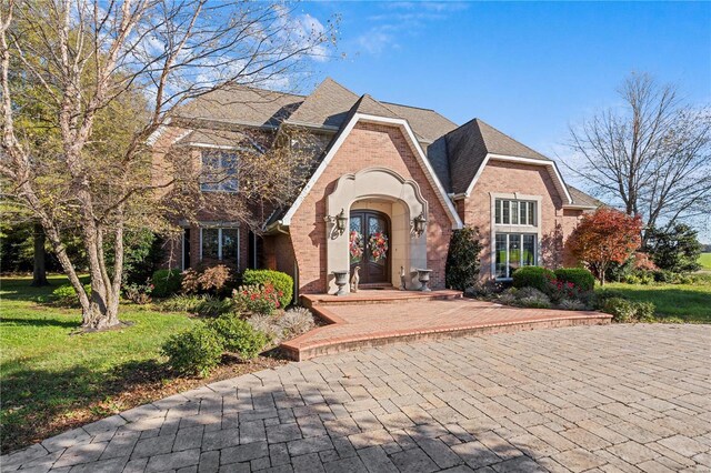view of front of home featuring french doors, brick siding, and a front yard