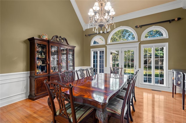 dining room with french doors, ornamental molding, a wainscoted wall, a chandelier, and light wood-type flooring