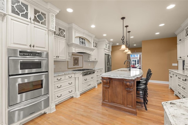 kitchen with a warming drawer, stainless steel appliances, white cabinets, light wood-type flooring, and recessed lighting