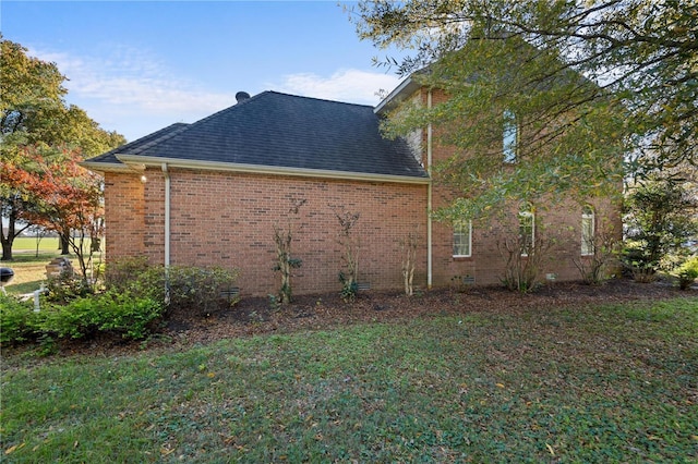 view of side of home featuring a lawn, brick siding, and roof with shingles