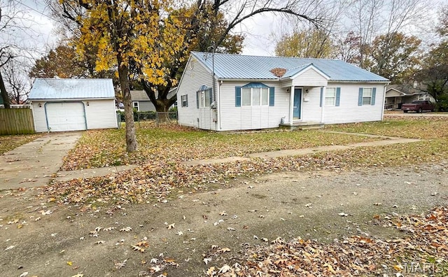 ranch-style home with driveway, an outbuilding, metal roof, fence, and a garage