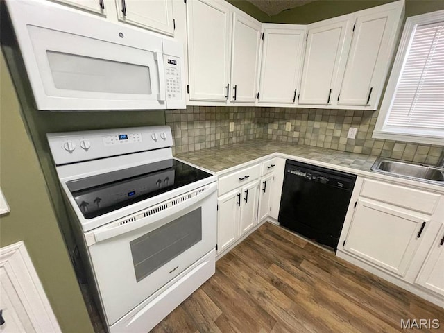 kitchen with white appliances, a sink, white cabinets, dark wood-type flooring, and tile counters
