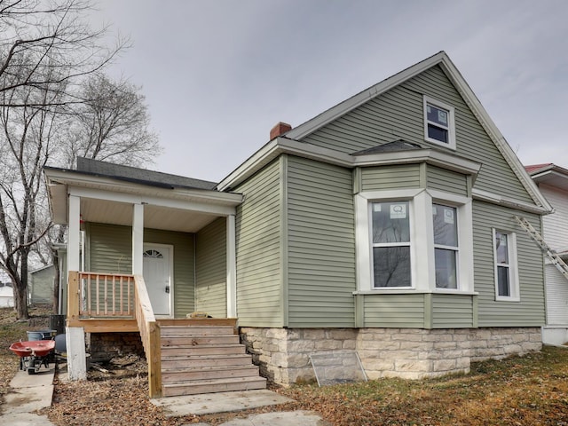 view of front facade featuring a porch and a chimney