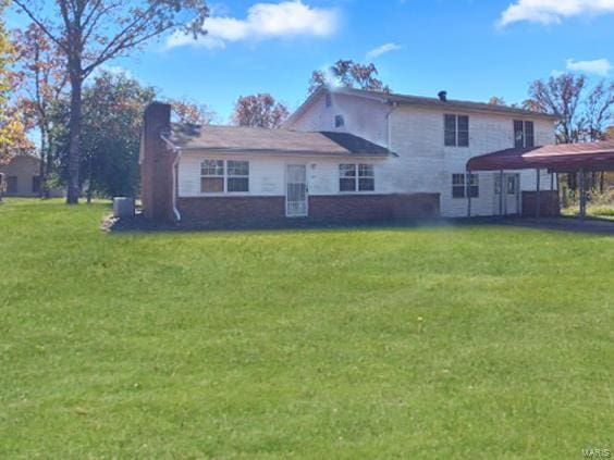 rear view of house featuring a lawn, a carport, and a chimney