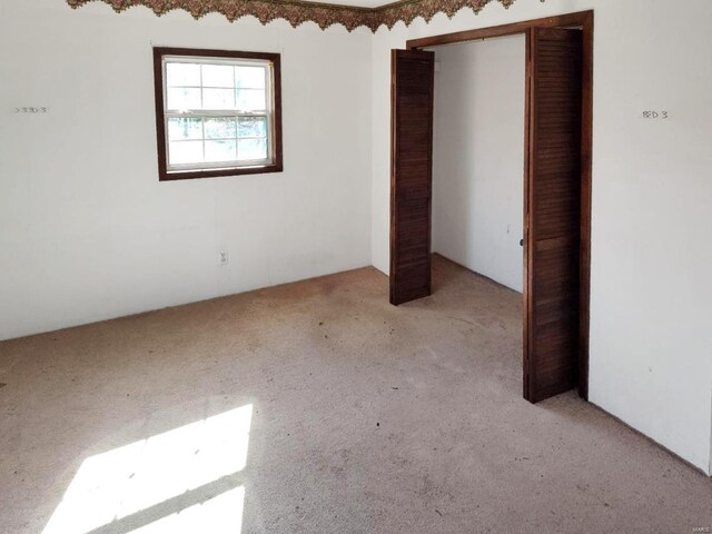 unfurnished bedroom with light carpet and a closet