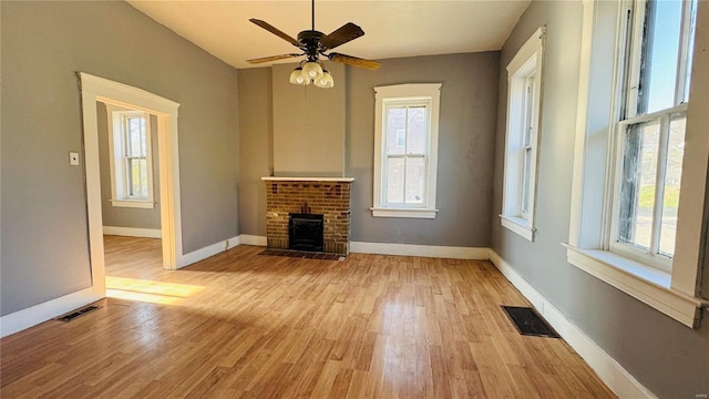 unfurnished living room featuring light wood-style flooring, healthy amount of natural light, and a ceiling fan