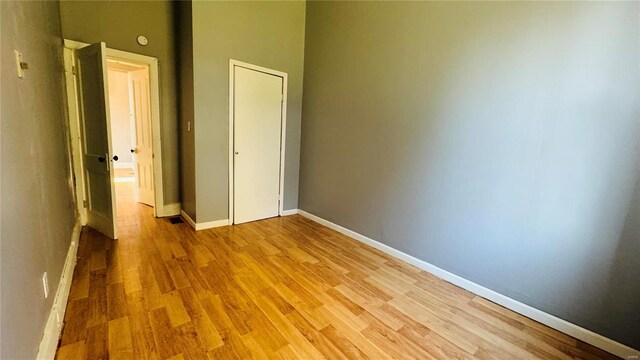 unfurnished bedroom featuring light wood-type flooring, baseboards, and a closet
