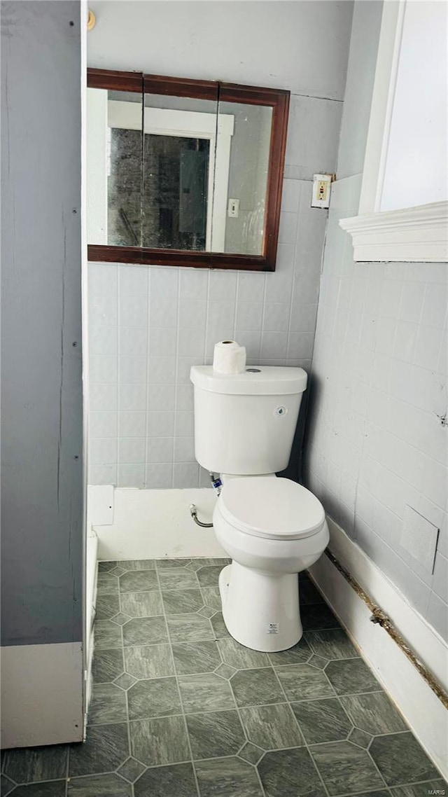 bathroom featuring toilet and tile walls