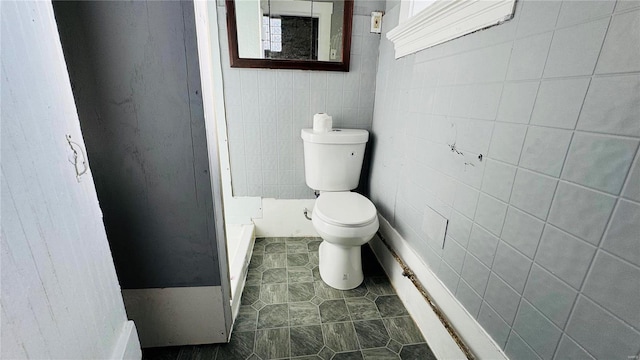 bathroom with toilet, tile walls, and tile patterned floors