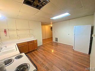 2447 E 24th St, Granite City, IL 62040 - kitchen with wood finished floors, white range with electric cooktop, brown cabinetry, a paneled ceiling, and a sink