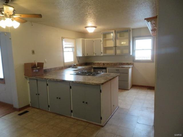 kitchen featuring a peninsula, a textured ceiling, ceiling fan, white cabinets, and baseboards