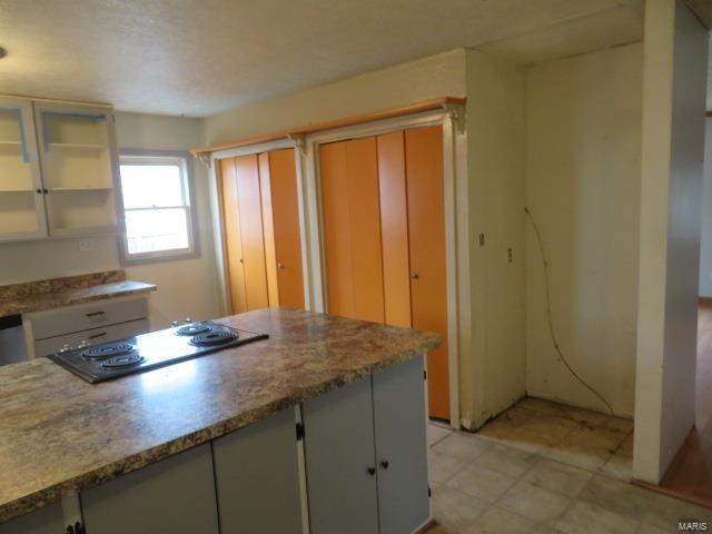 kitchen featuring electric cooktop, open shelves, white cabinetry, and light countertops