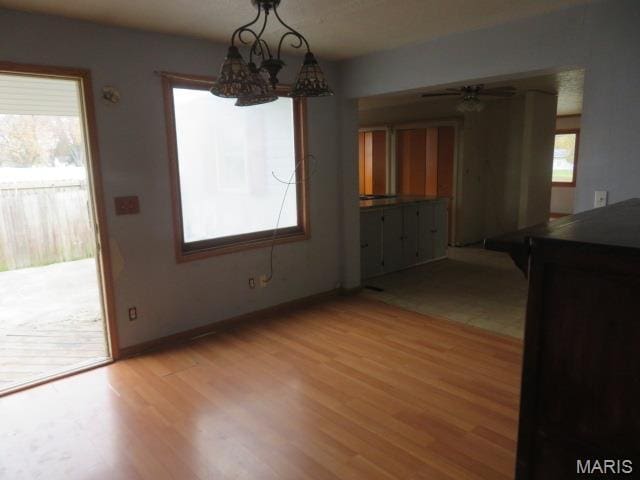 817 S Montgomery Ave, Litchfield, IL 62056 - unfurnished dining area featuring light wood-style flooring, a chandelier, baseboards, and a ceiling fan