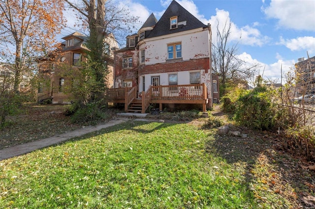 back of house featuring a yard, a deck, and brick siding