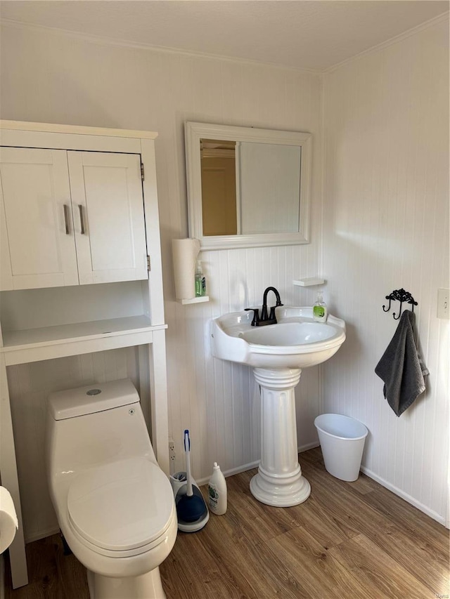 bathroom featuring wood finished floors, toilet, ornamental molding, and baseboards