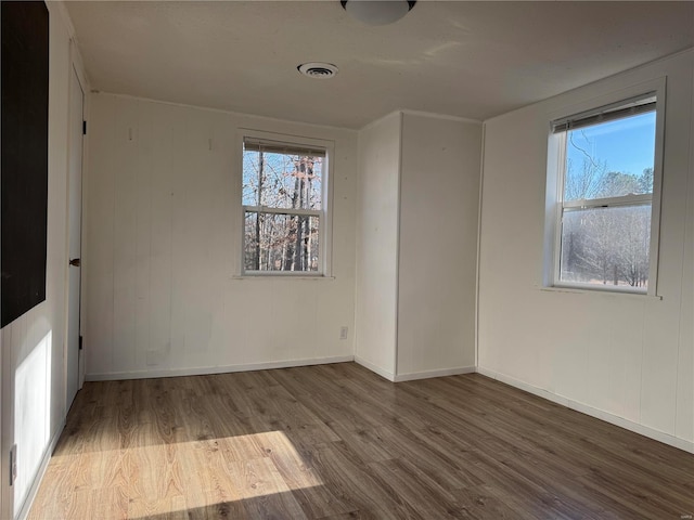 unfurnished room featuring wood finished floors, healthy amount of natural light, and baseboards
