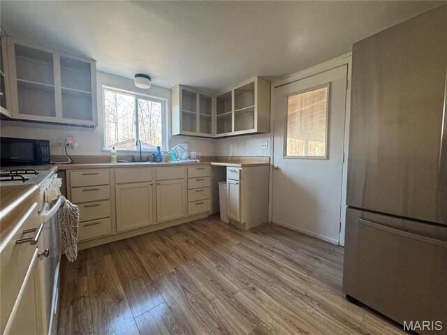 839 Bluebird Ln, Doniphan, MO 63935 - kitchen featuring freestanding refrigerator, white gas range oven, black microwave, light wood-style flooring, and a sink