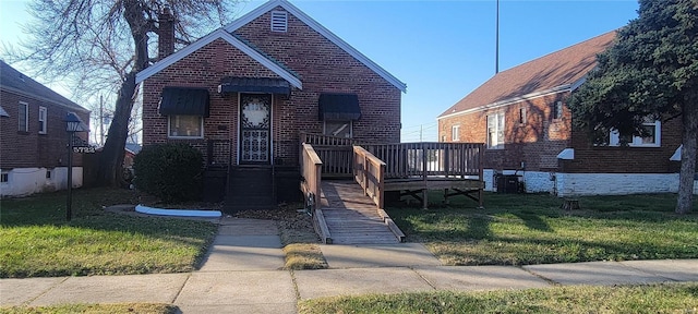 bungalow-style home featuring brick siding, a front yard, and a deck