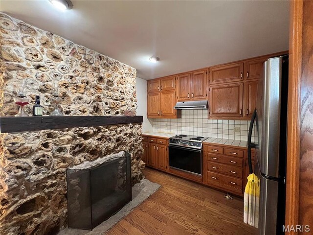 315 E Madison St, Paris, MO 65275 - kitchen with freestanding refrigerator, range with electric stovetop, tile counters, light wood-style flooring, and under cabinet range hood