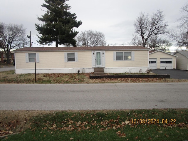 manufactured / mobile home with an outbuilding, entry steps, a garage, and asphalt driveway