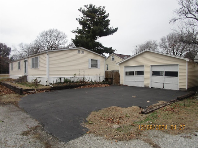 view of property exterior with a detached garage, an outbuilding, and fence