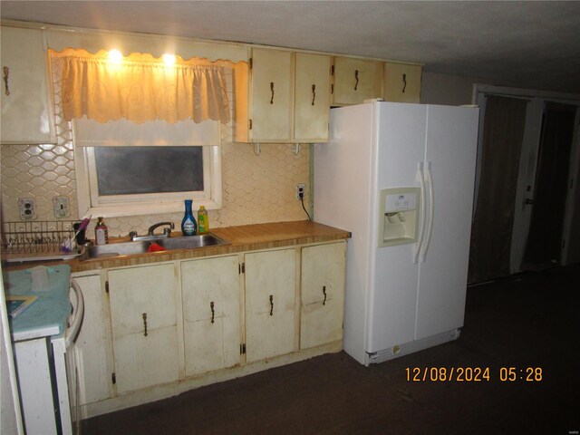 kitchen featuring white refrigerator with ice dispenser, decorative backsplash, a sink, and light countertops