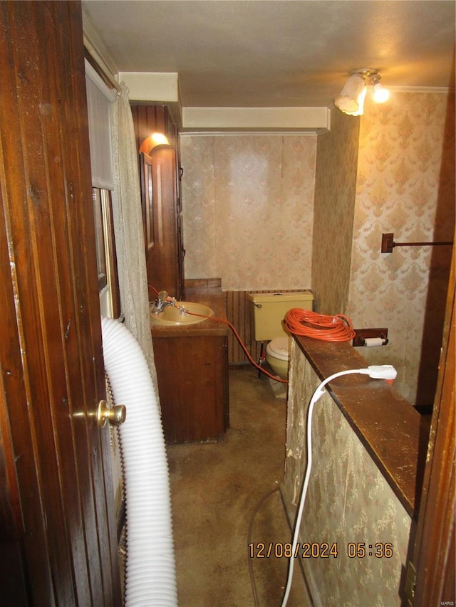 bathroom featuring vanity, toilet, and wallpapered walls