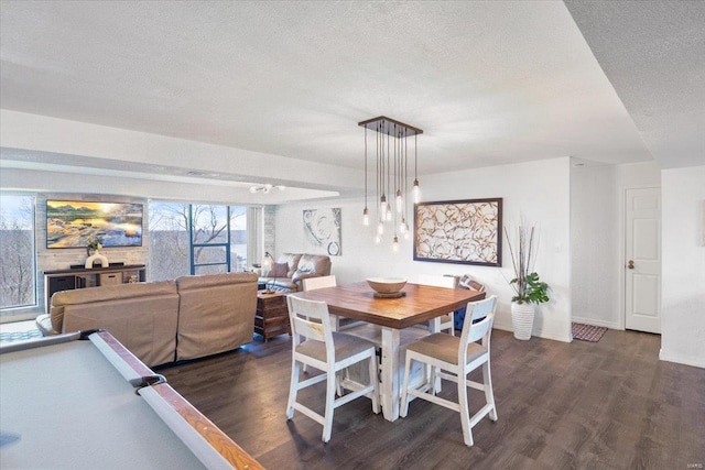 dining space with dark wood-style flooring, a textured ceiling, and baseboards