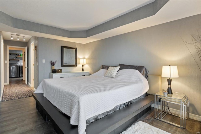 bedroom featuring wood finished floors, baseboards, and washer / dryer