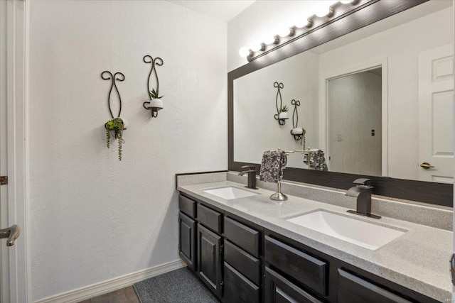 full bath with baseboards and double vanity