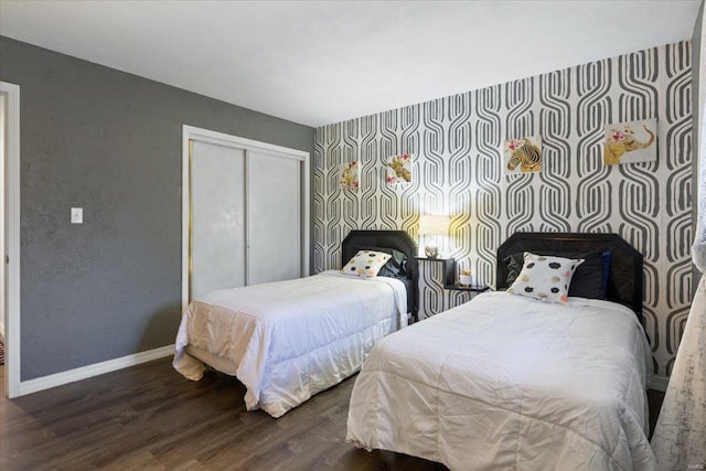 bedroom with wood finished floors, baseboards, and a closet