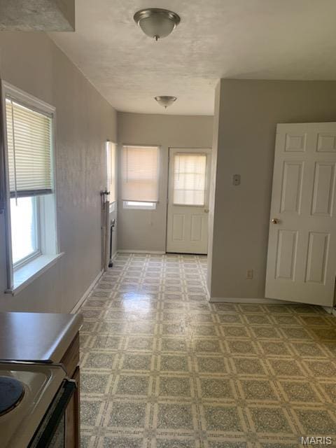 hallway with plenty of natural light, baseboards, and tile patterned floors