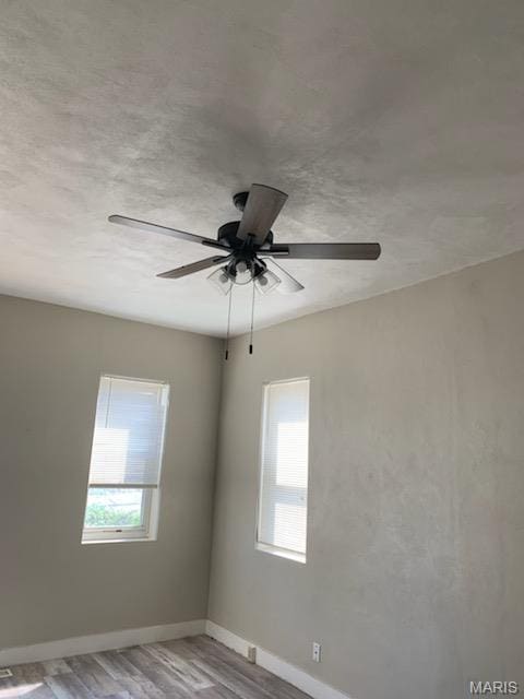unfurnished room featuring wood finished floors, baseboards, and ceiling fan