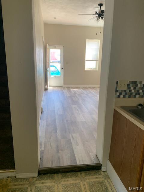 corridor featuring healthy amount of natural light, light wood-style flooring, and baseboards