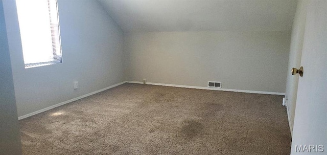 additional living space with lofted ceiling, dark colored carpet, and baseboards