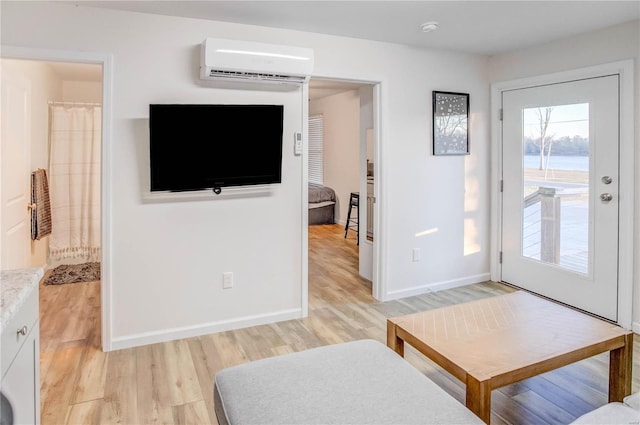1100 W Main St, Grafton, IL 62037 - living area featuring an AC wall unit, light wood-style flooring, and baseboards