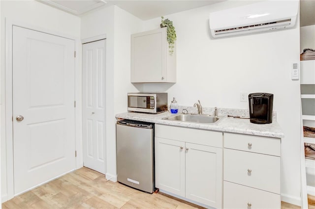 1100 W Main St, Grafton, IL 62037 - kitchen featuring fridge, stainless steel microwave, an AC wall unit, a sink, and light wood-type flooring