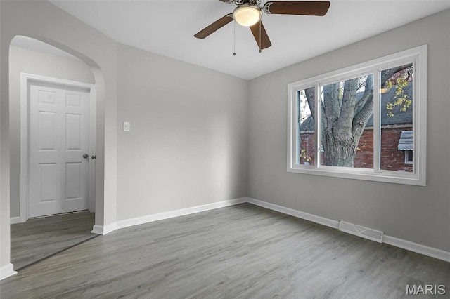 1021 Lakeview Ave, Saint Louis, MO 63138 - empty room with wood finished floors, baseboards, ceiling fan, and arched walkways