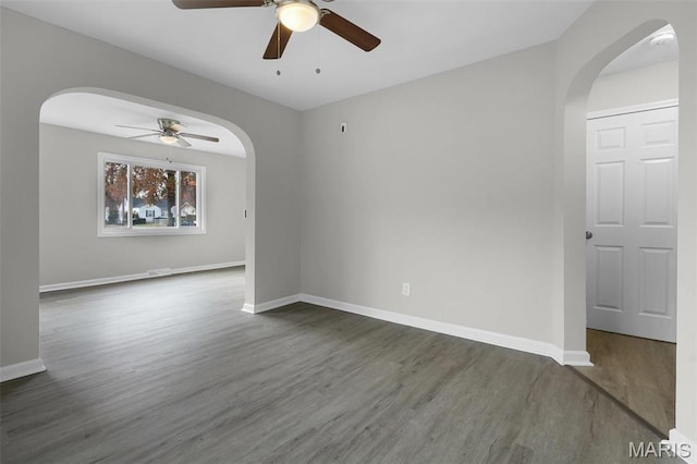 1021 Lakeview Ave, Saint Louis, MO 63138 - empty room featuring ceiling fan, arched walkways, dark wood finished floors, and baseboards