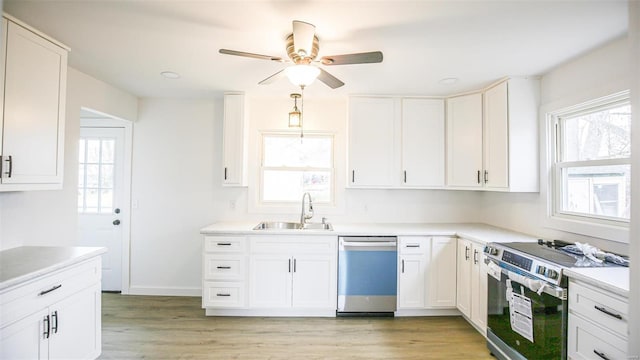404 Lueking Dr, De Soto, MO 63020 - kitchen with appliances with stainless steel finishes, a sink, a ceiling fan, white cabinetry, and light countertops